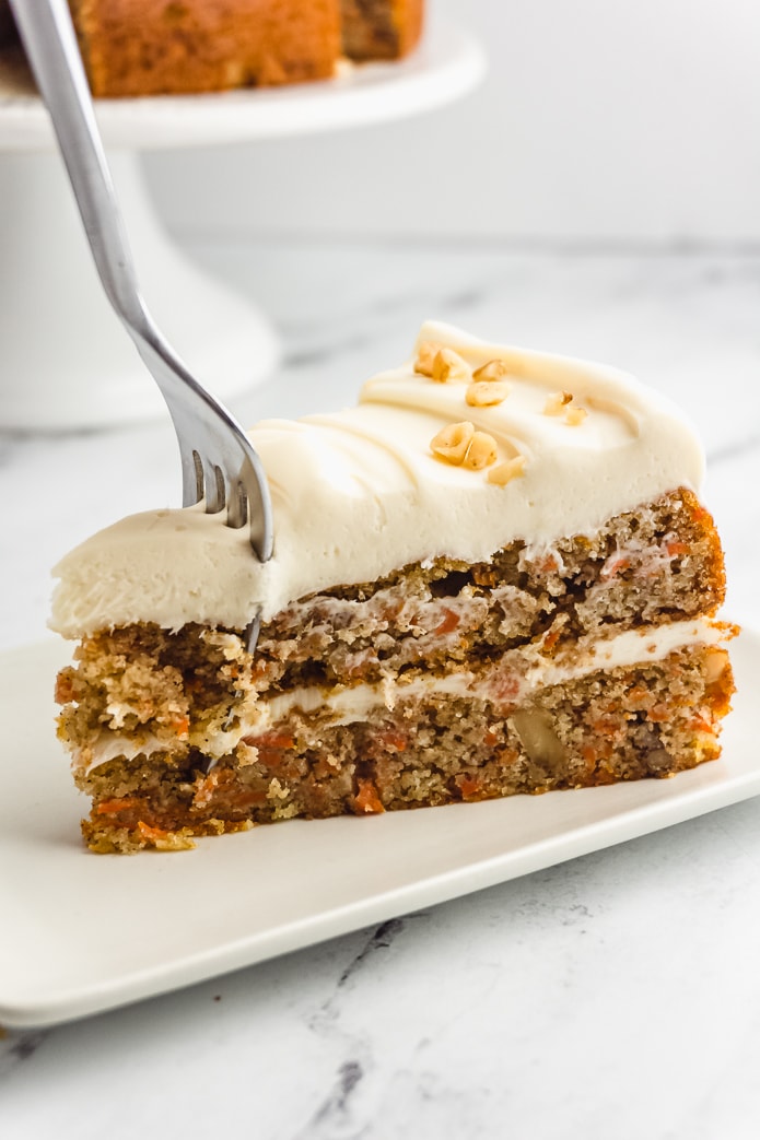 fork in a piece of keto carrot cake with cream cheese frosting